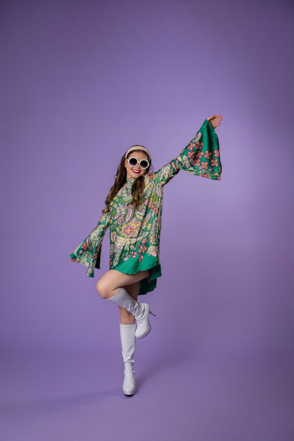 Fashion model in green floral kimono and white boots poses dynamically against purple background in editorial series.