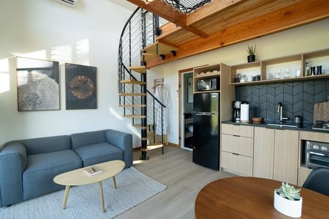 Modern loft apartment interior with wooden floors, white cabinets, and a gray sectional sofa in an open floor plan.