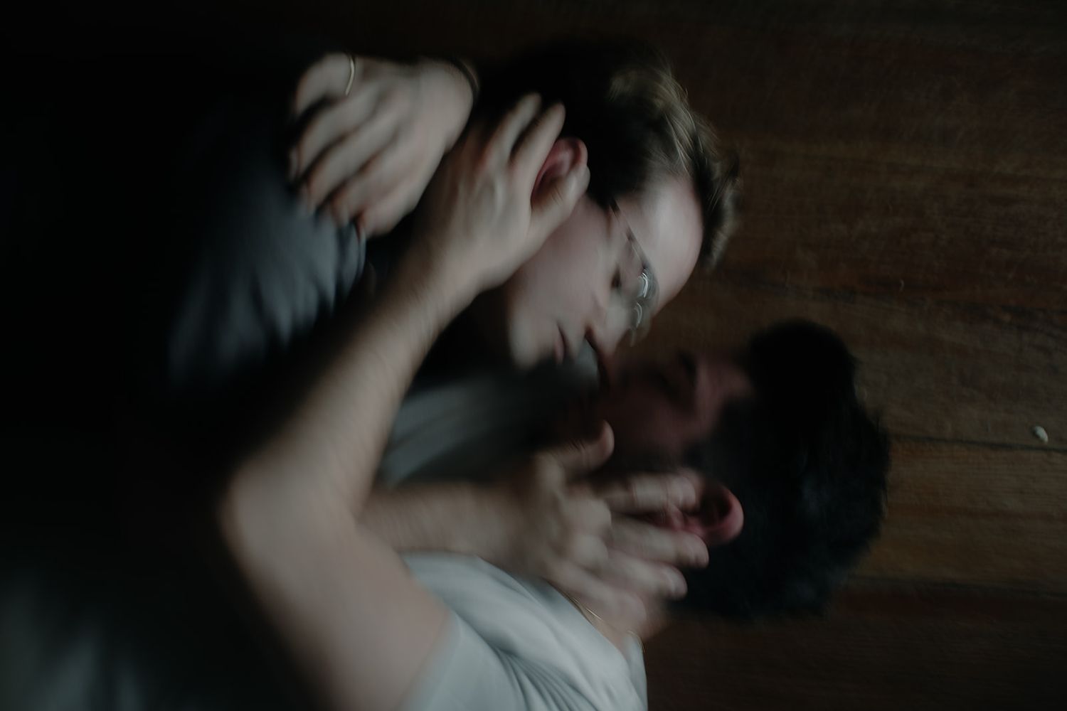 Intimate close-up photo showing a tender embrace between two people on wooden flooring.