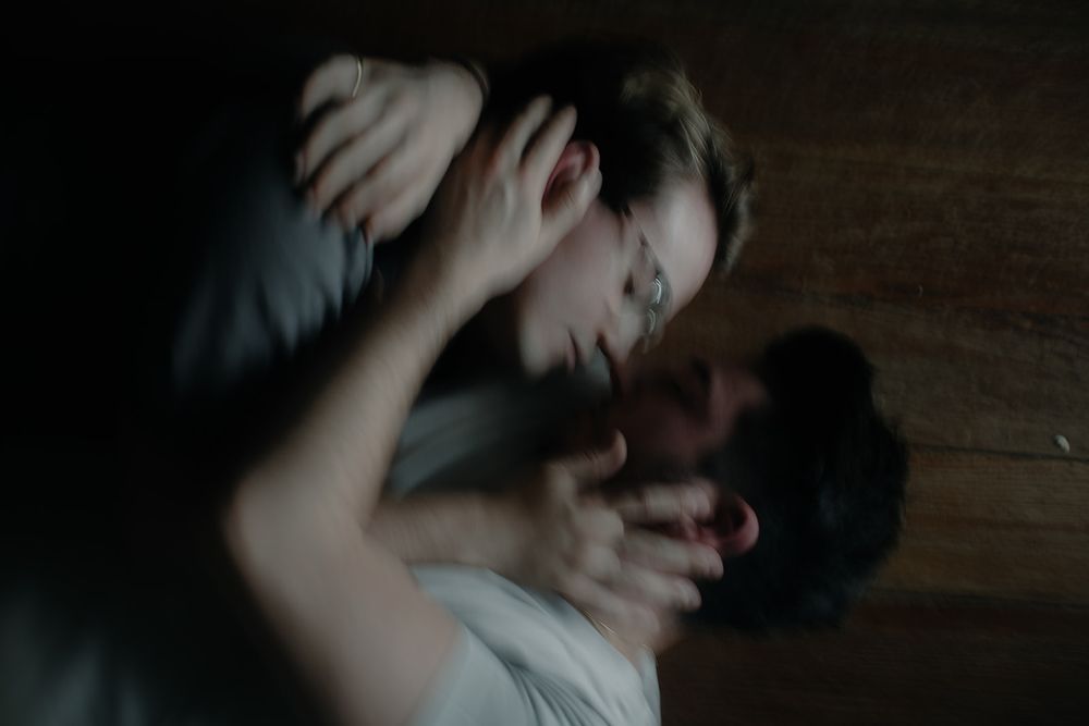 Intimate close-up photo showing a tender embrace between two people on wooden flooring.