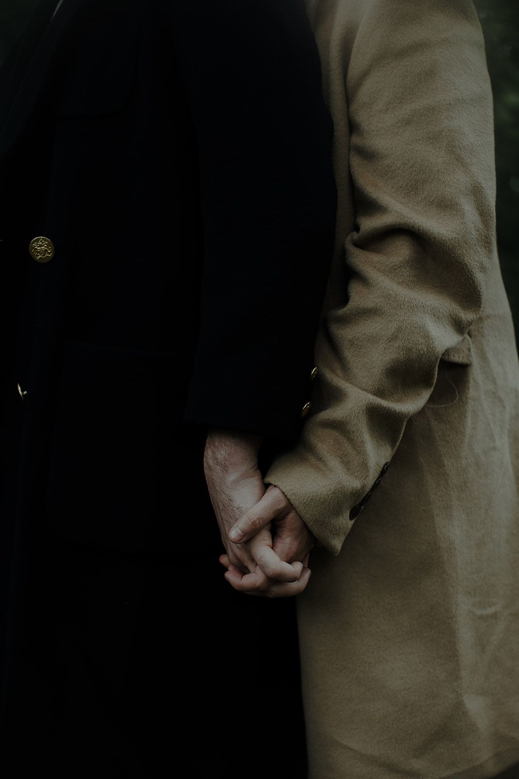 Close-up of hands clasped together against a dark background showing a contemplative moment.