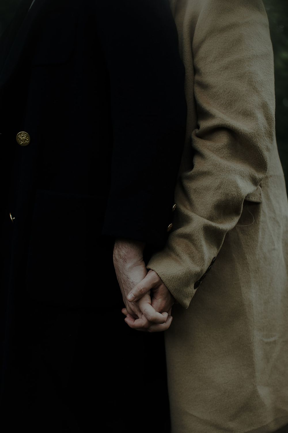 Close-up of hands clasped together against a dark background showing a contemplative moment.