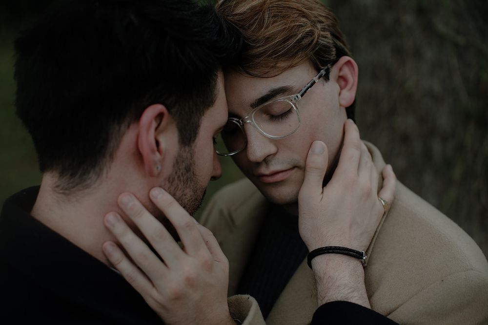 Two people share a close emotional moment in a shadowy outdoor setting.
