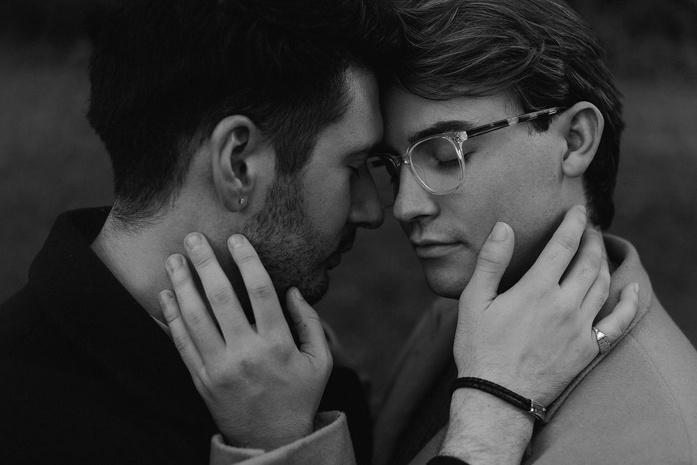 Intimate black and white portrait of a couple in a tender moment with hands gently touching faces.