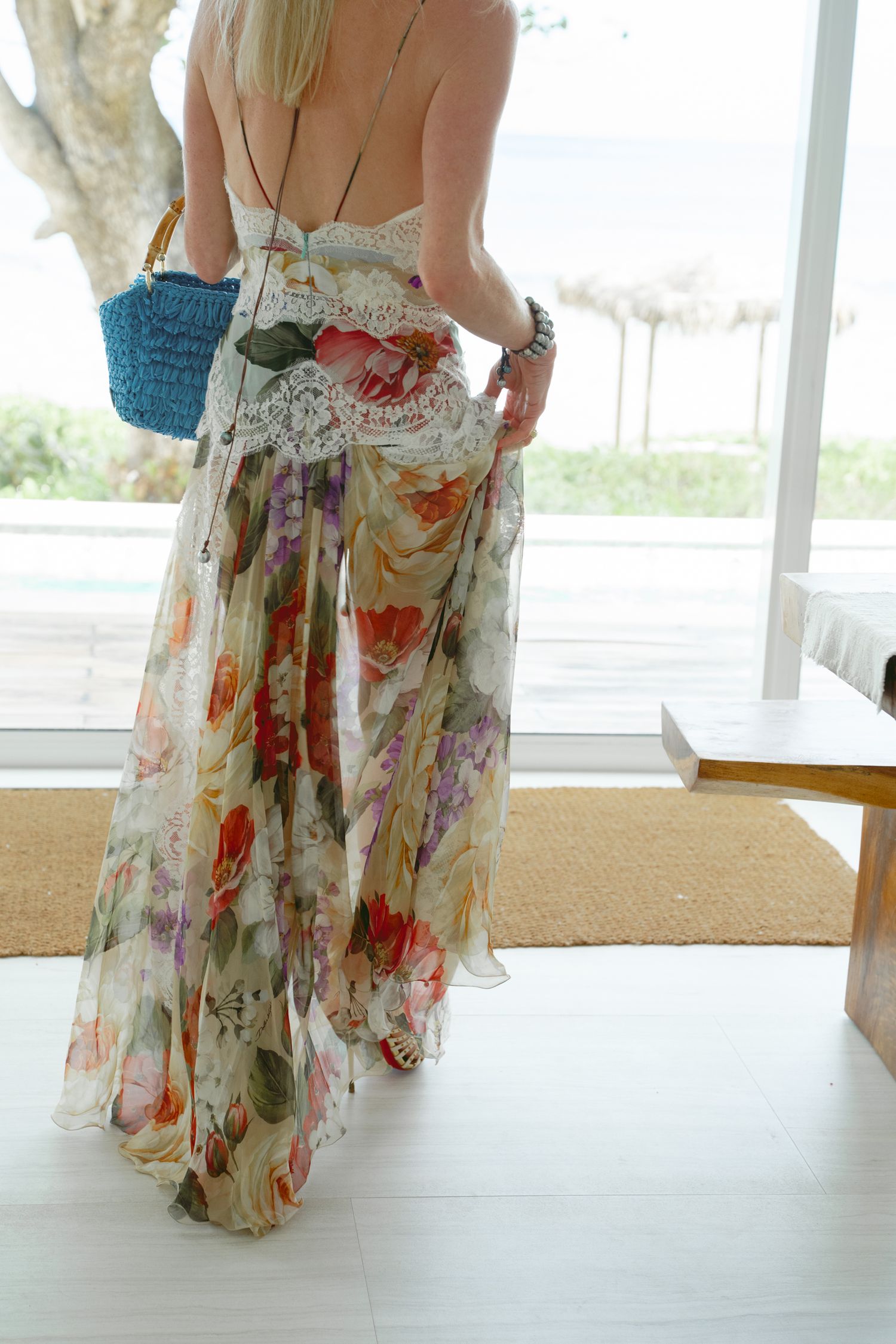 Flowy floral maxi dress with watercolor print seen from behind in a sunlit room.