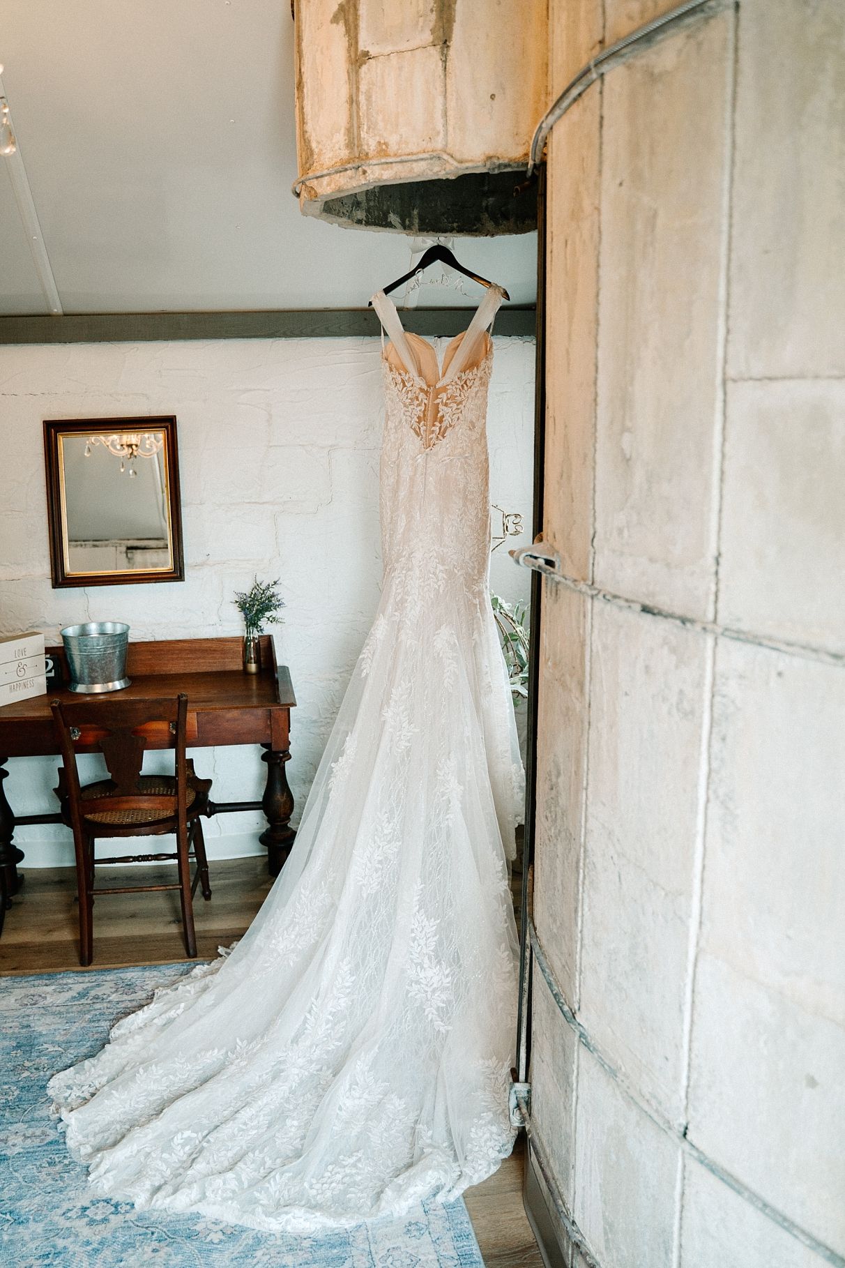Elegant lace mermaid wedding gown hanging in rustic silo bridal suite.