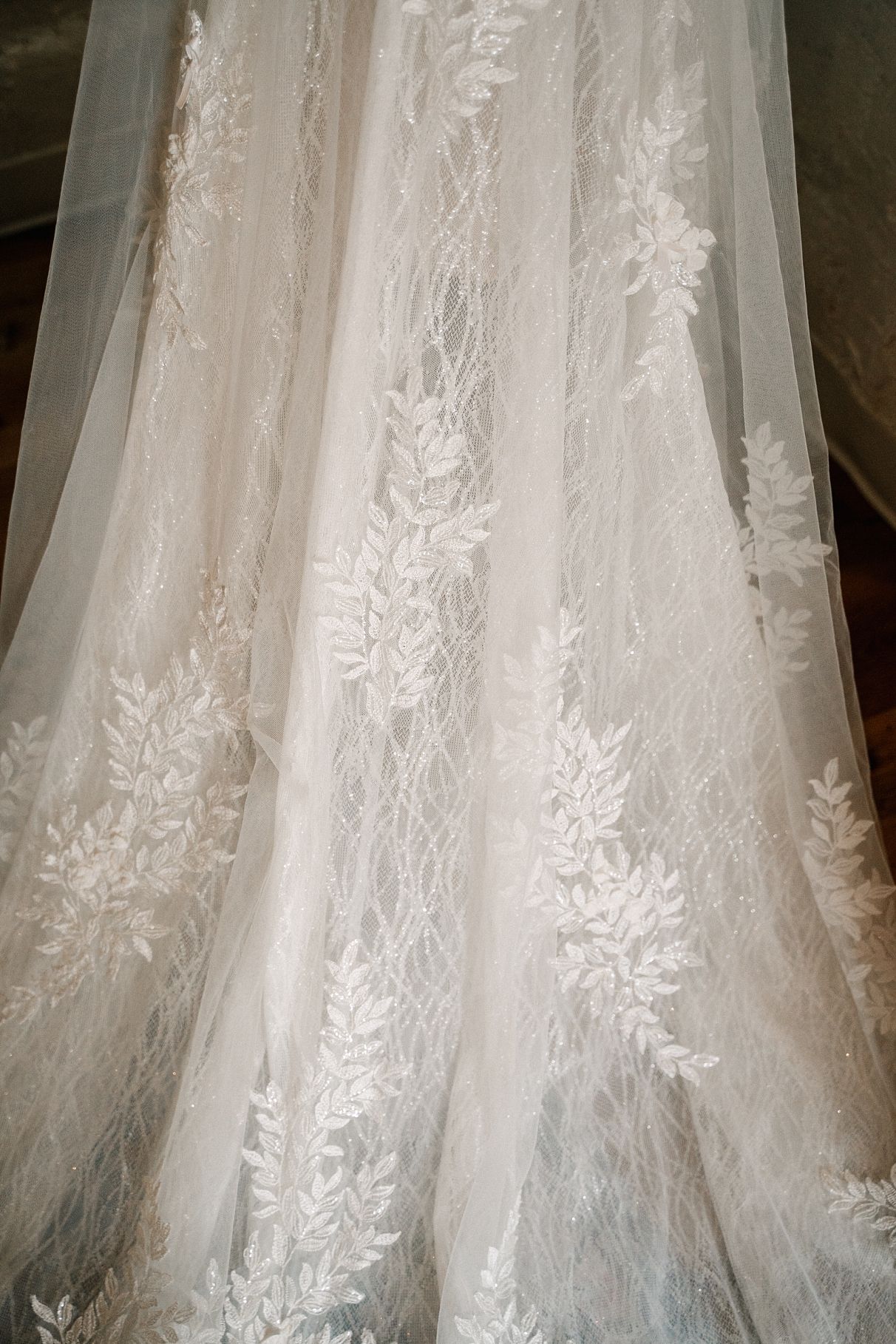 Close-up detail of delicate floral leaf lace pattern on a bridal wedding gown.