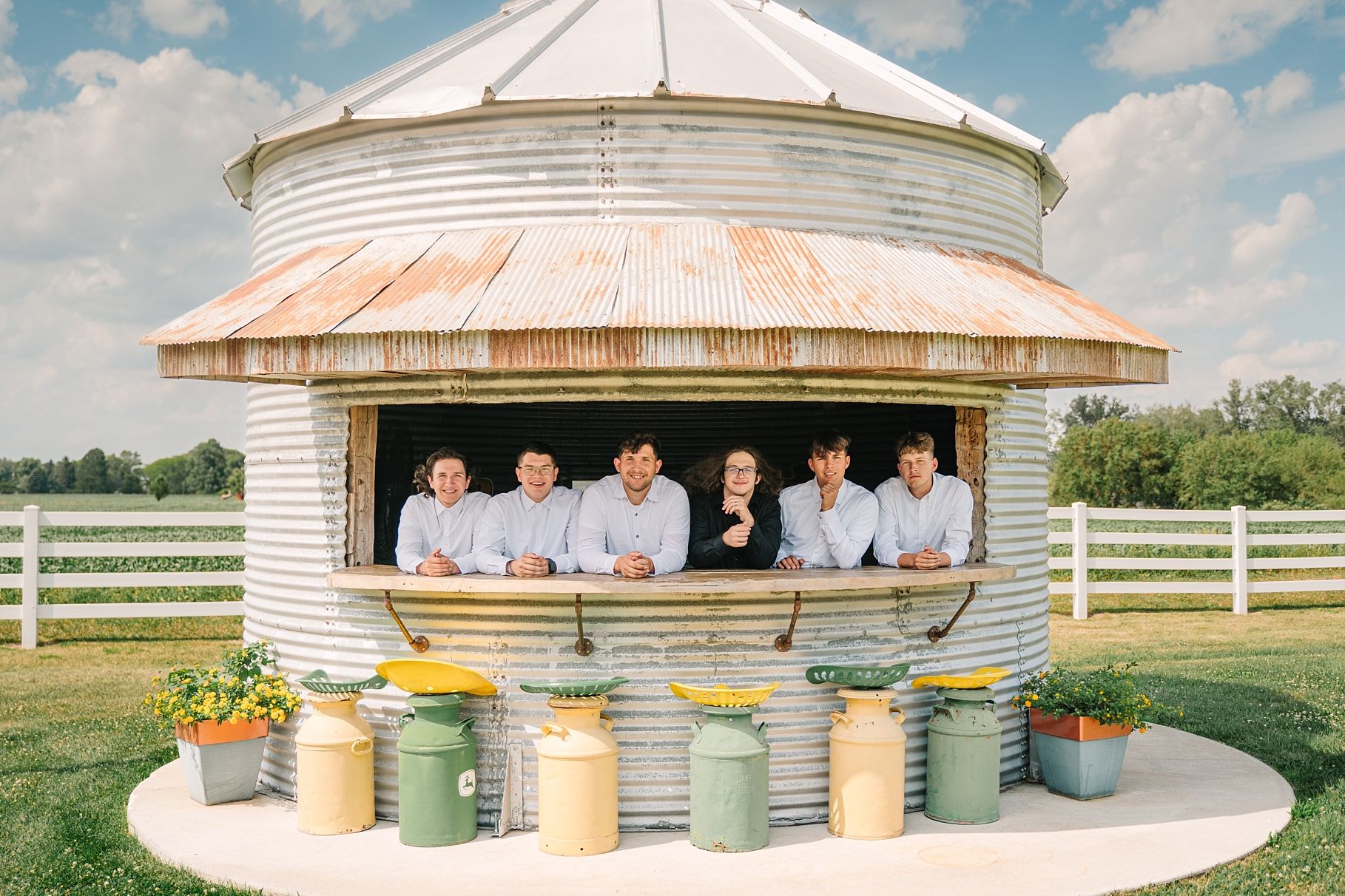 Group of people lean over the edge of a rustic grain bin silo on a farm.