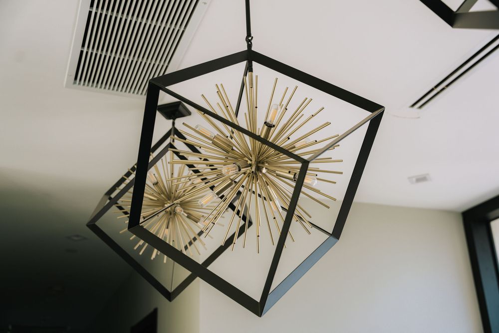 Modern gold starburst chandelier with geometric black frame hangs elegantly from a white ceiling.