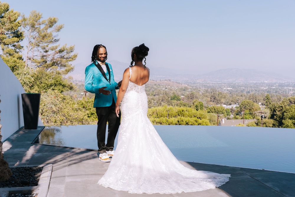 A scenic outdoor wedding venue overlooking a city skyline with mountains in the background on a sunny day.