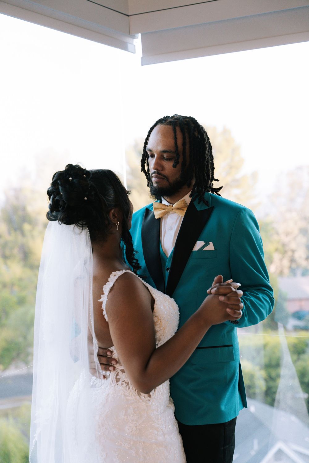 Wedding couple dancing together in formal attire with turquoise accents.