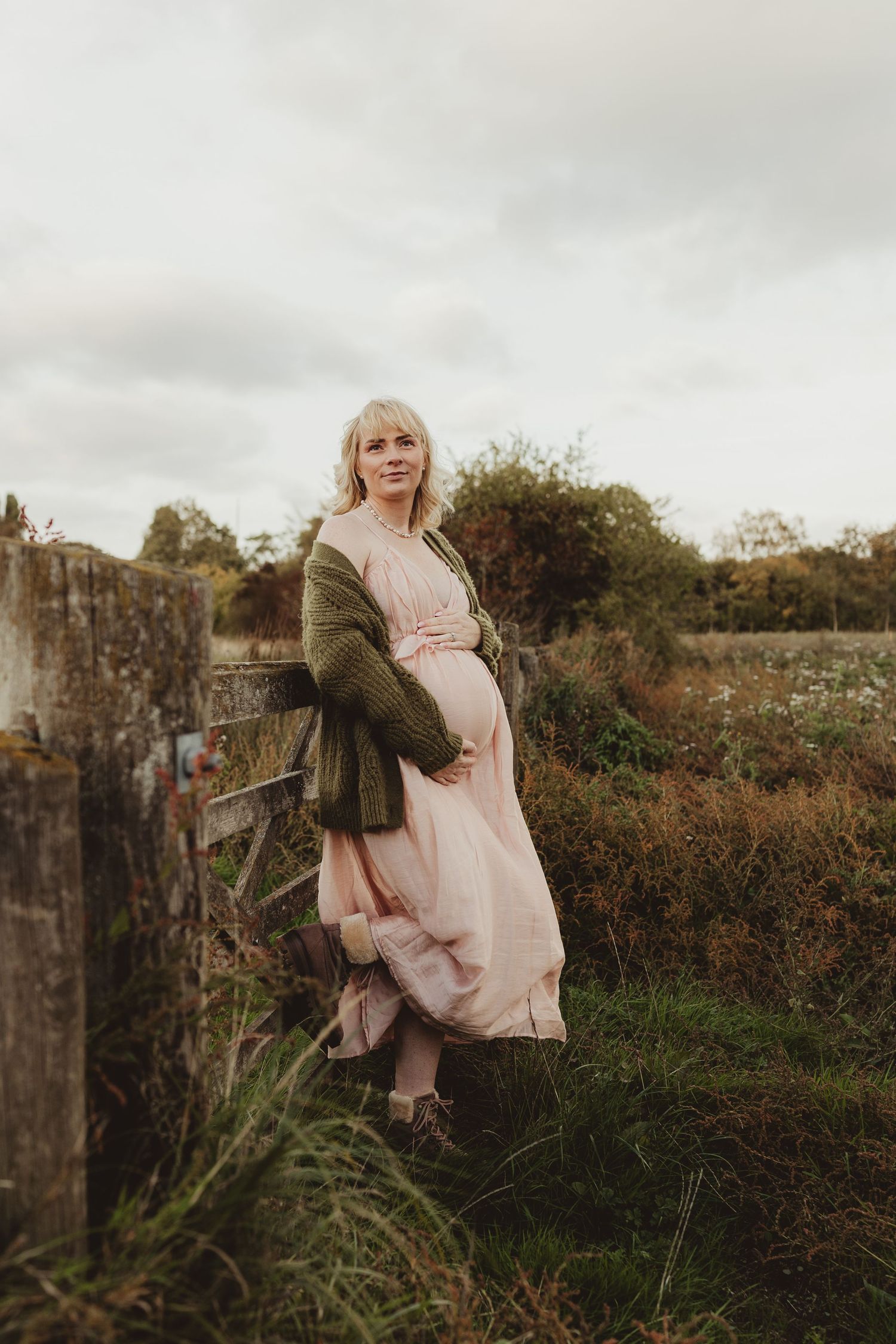 A romantic couple in vintage-style clothing lies on grass surrounded by delicate white wildflowers and greenery.