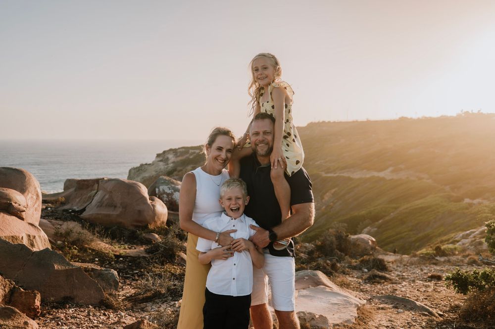 Natural light family photography session during golden hour at St Blaize, highlighting warm tones, and the rugged beauty of the coastline