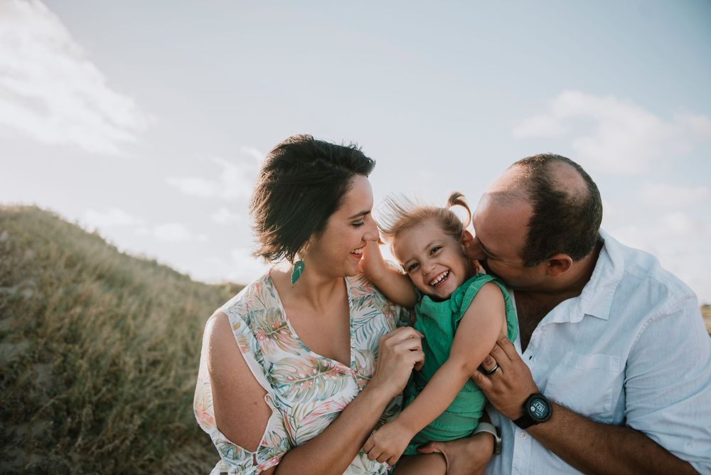 Parents tickling their young daughter on the beach at Gouritsmond, capturing a playful and joyful family moment by the sea.