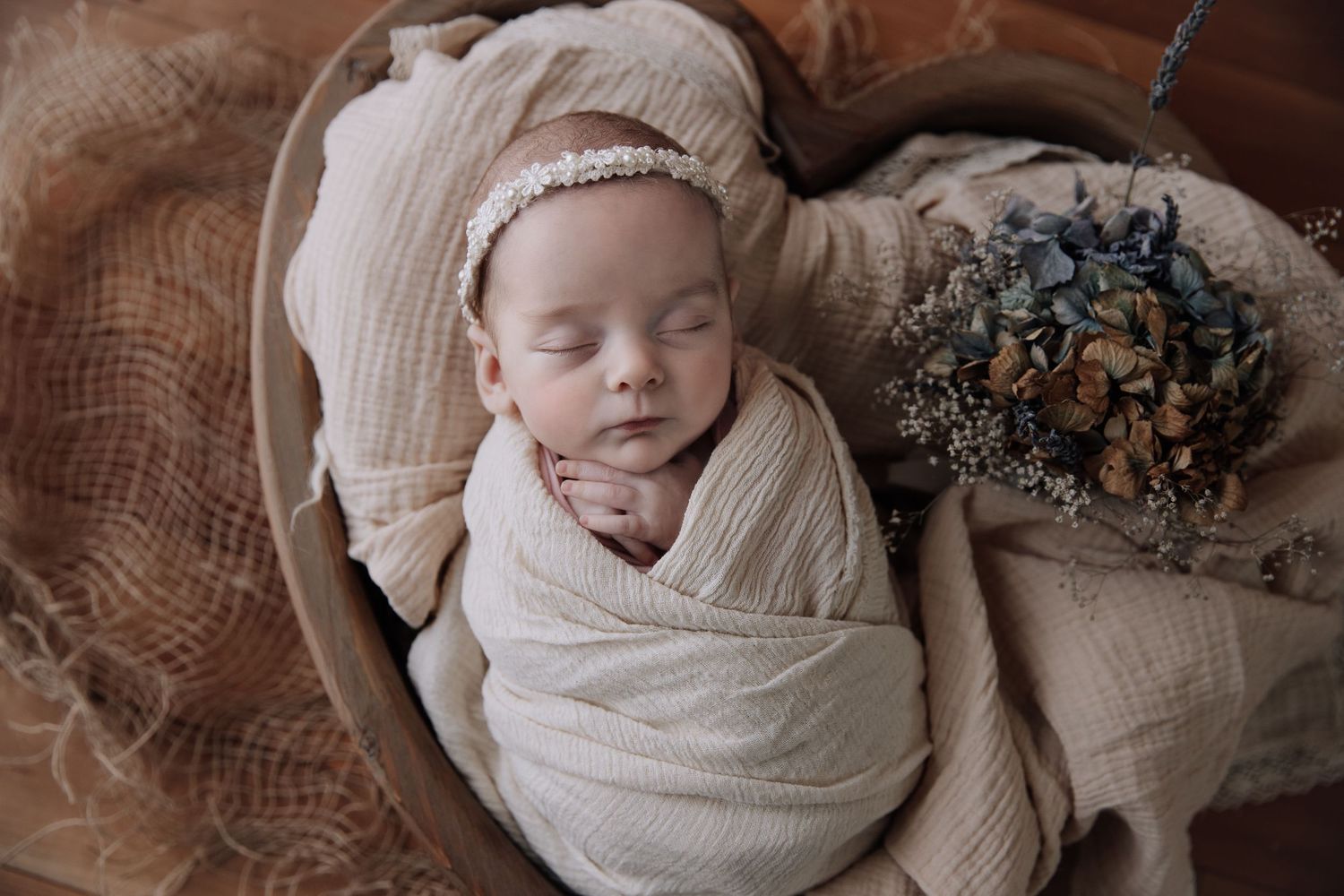 A collage of six photos showing a sleeping newborn baby swaddled in white fabric against a neutral backdrop.