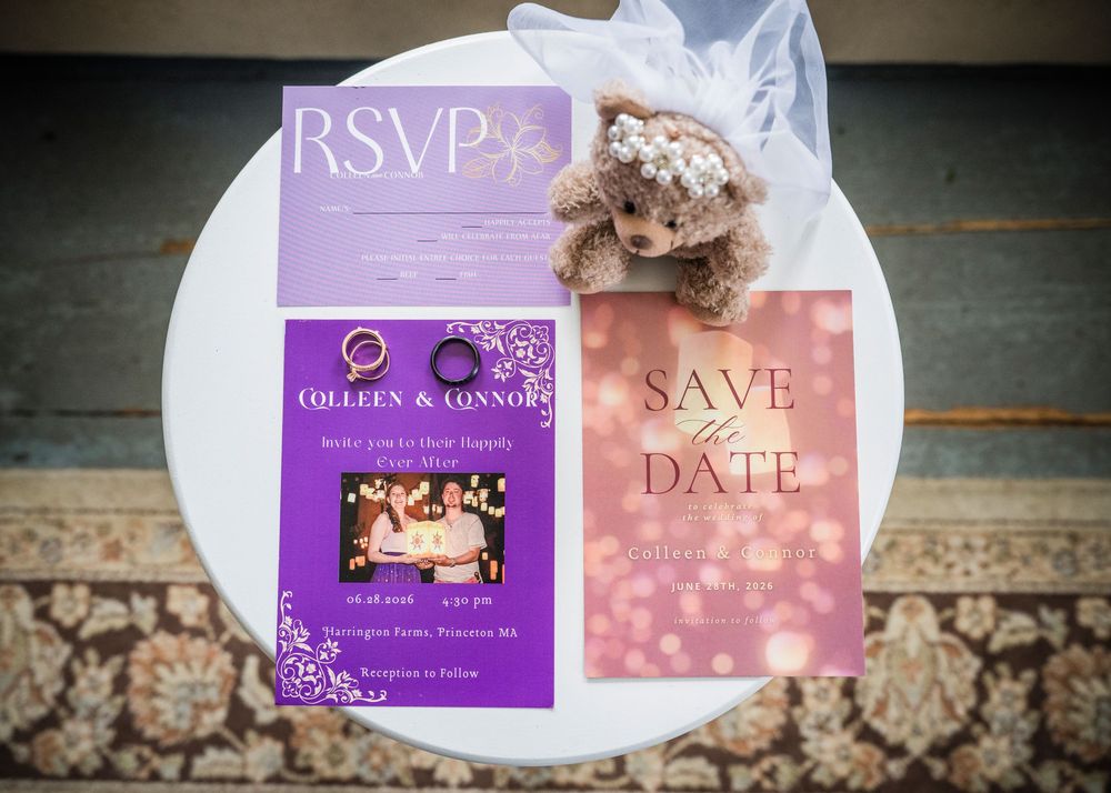 Wedding stationery flat lay featuring RSVP card, save the date, and invitation with a small teddy bear on a white table.
