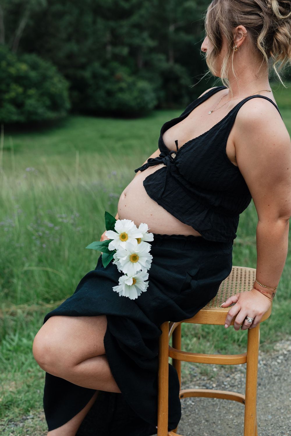 A progression of maternity photos shows a growing baby bump adorned with white daisies while seated in a wooden chair.