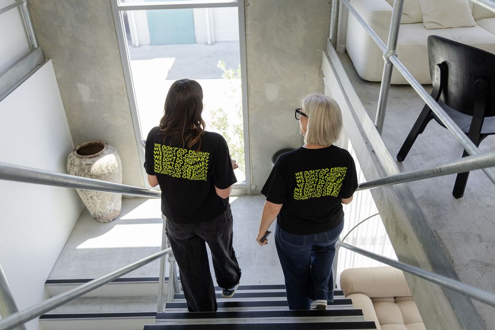 Two people in black shirts walking and talking  inside a modern building