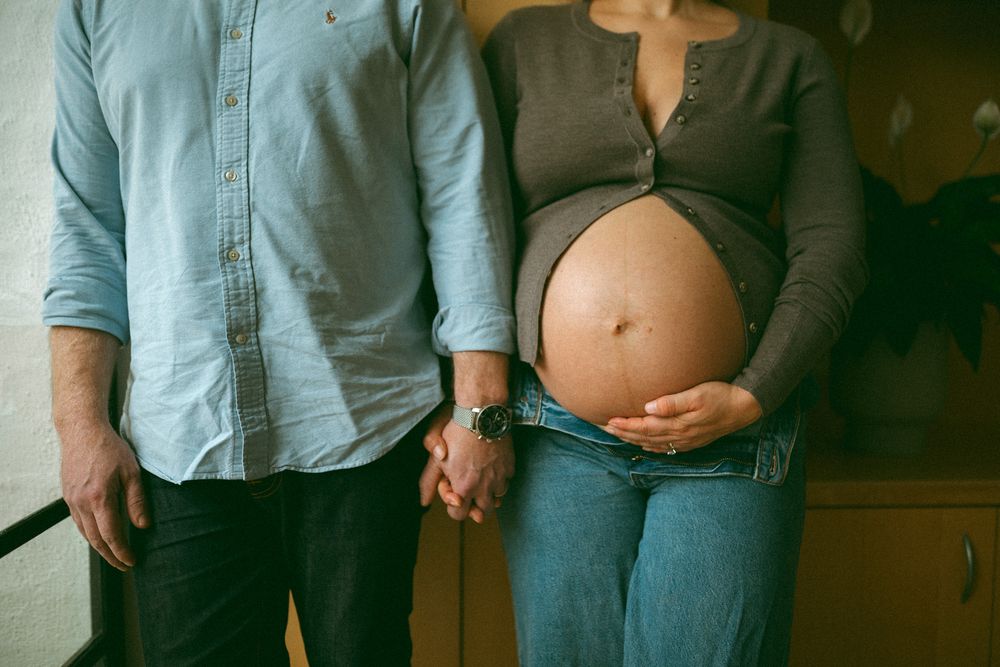 Series of cropped torso shots showing expectant parents holding hands and embracing.