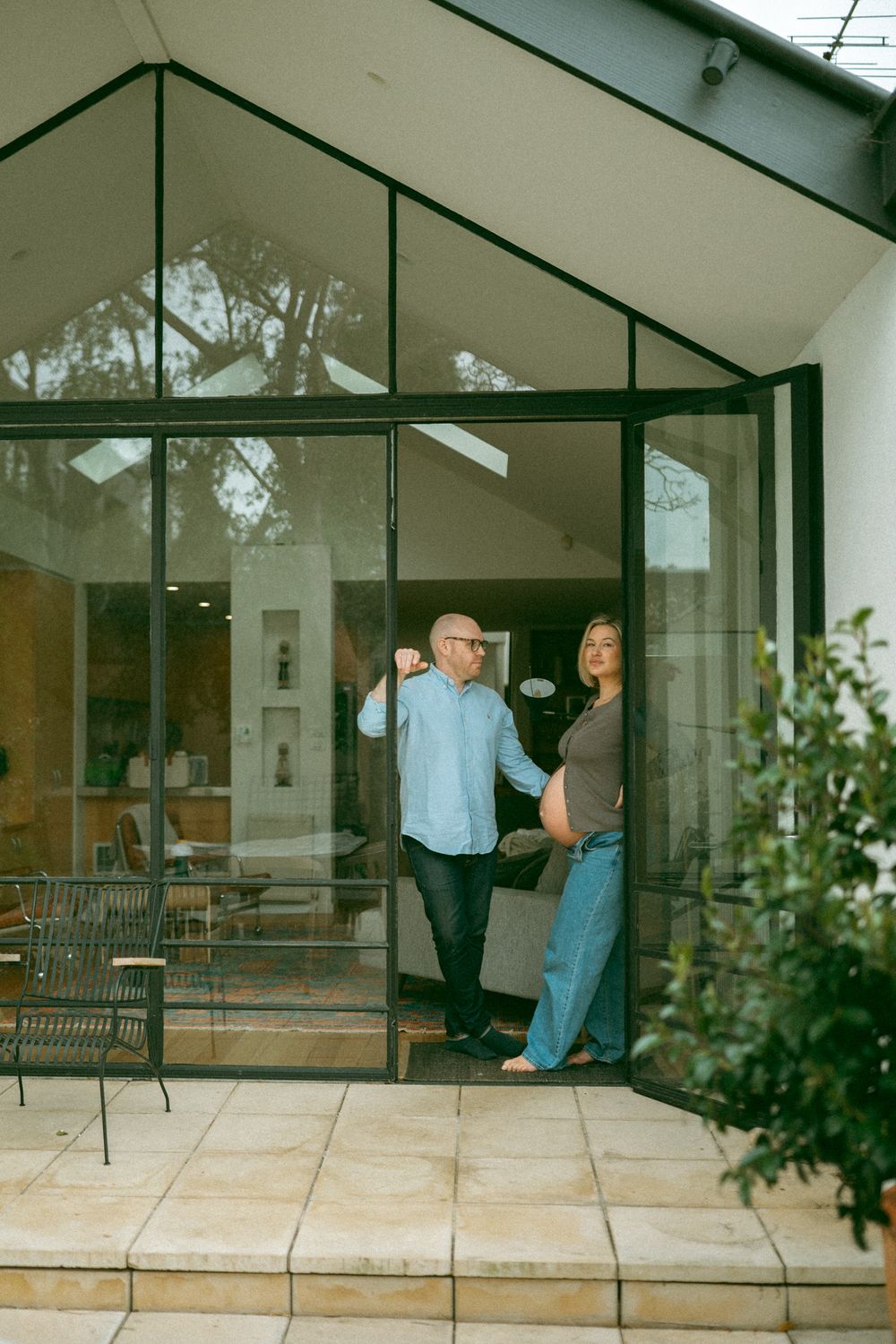 A sequence of images showing someone leaning and falling against a glass window pane of a modern house.