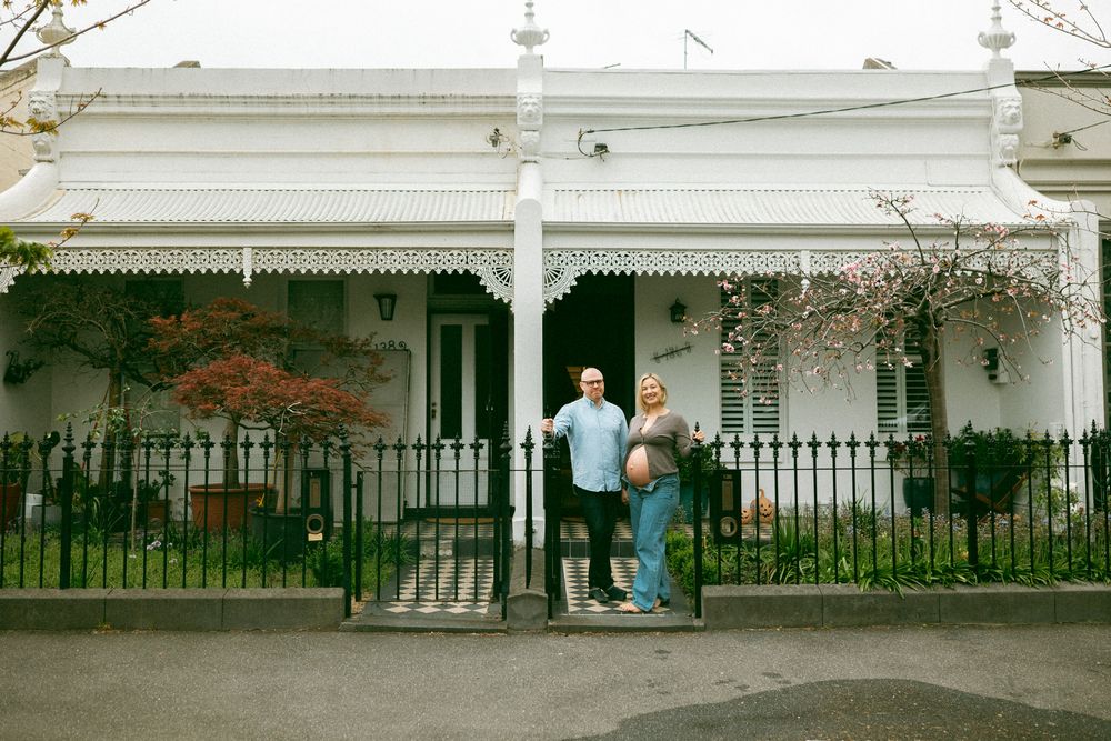 A series of connected white porch railings and columns along a historic building facade in a garden setting.