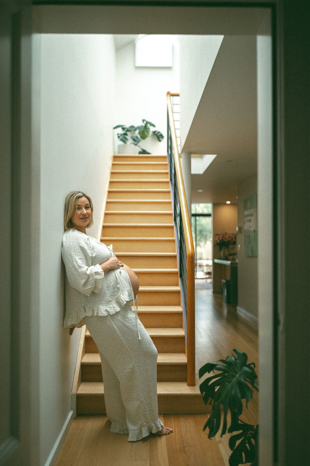 A maternity photo series showing progression of pregnancy in artistic poses along a staircase with natural lighting.