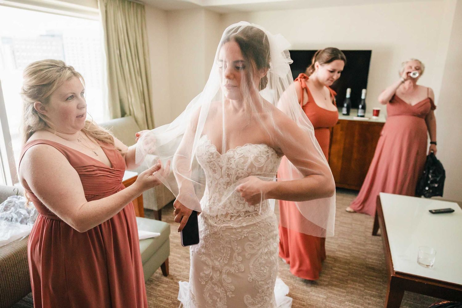 Bride having her veil adjusted by a bridesmaid during wedding morning preparations in Boston