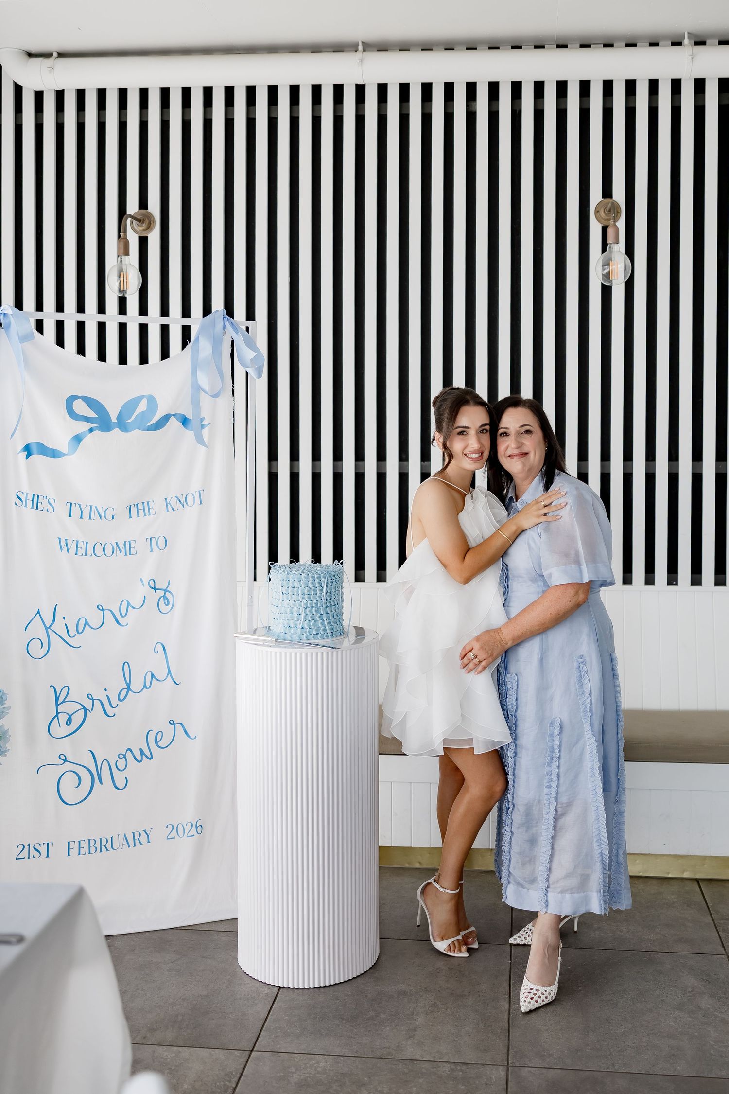 Modern bridal shower setup featuring black and white striped walls and welcome signs in light blue lettering.