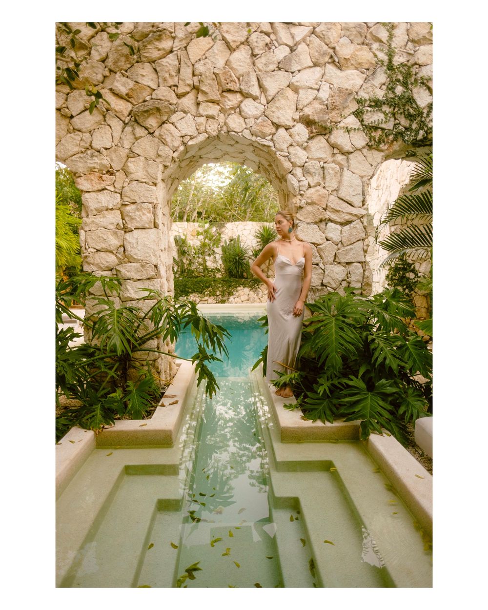 Elegant stone-walled garden space with a sunken rectangular pool area surrounded by tropical plants.