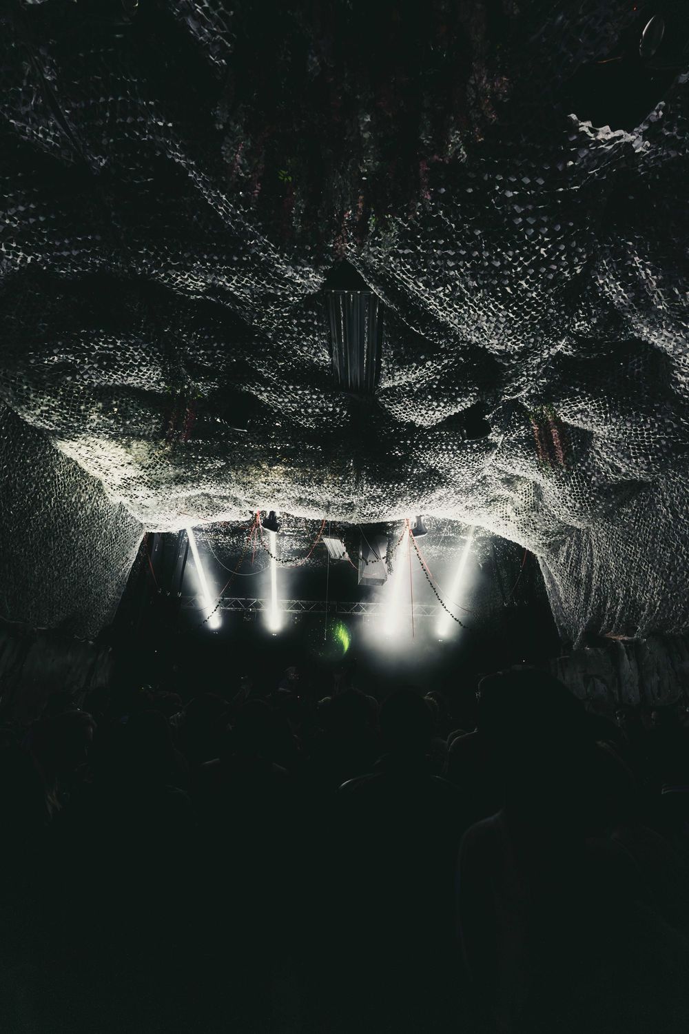 Underground cave tunnel illuminated by spotlights reveals dark rocky formations and geological features.