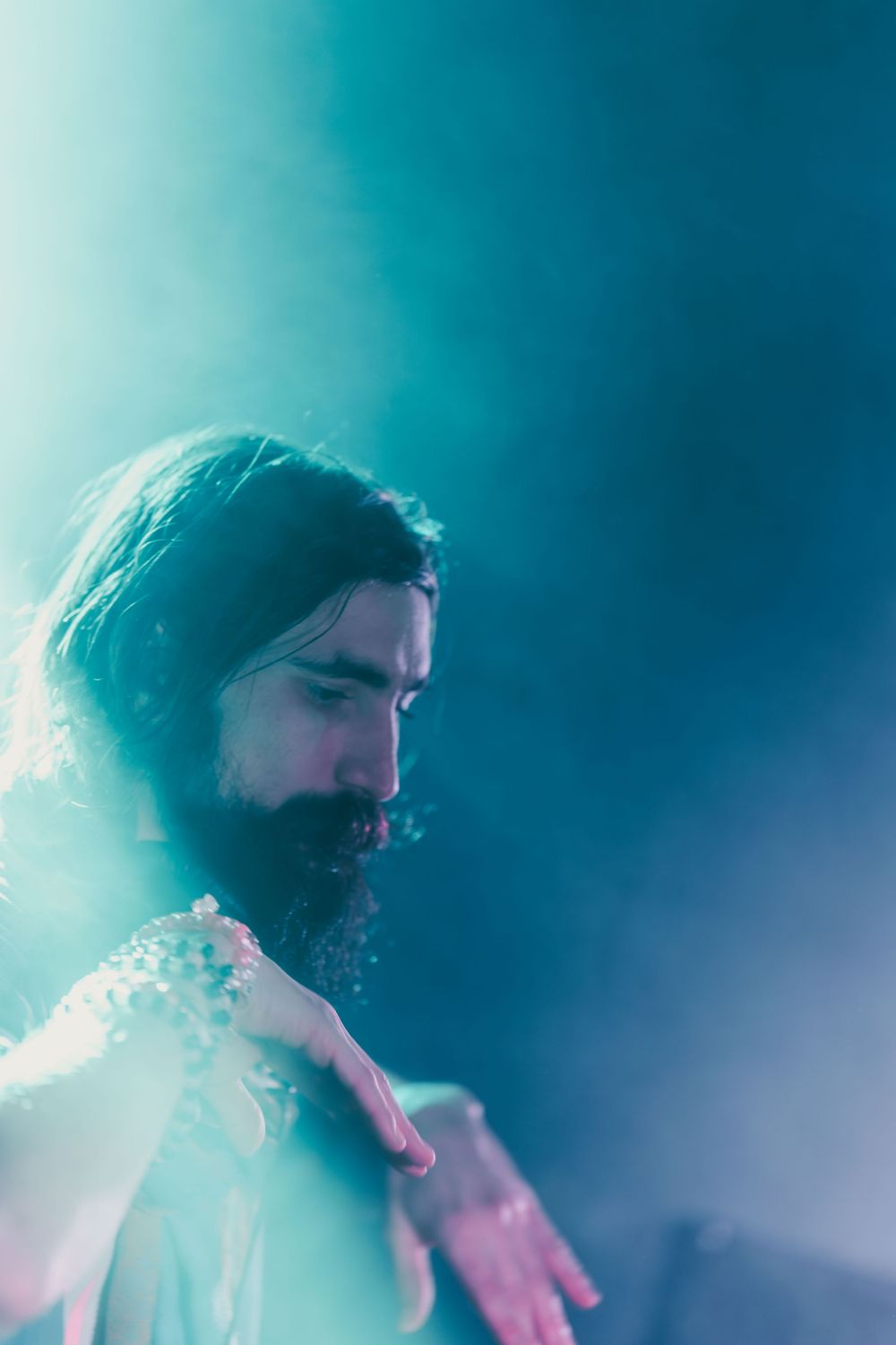 A person with facial hair is illuminated by ethereal blue lighting in a series of profile shots.