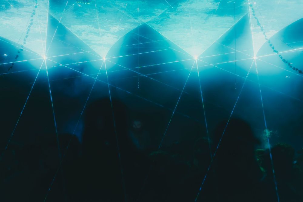 Abstract blue geometric pattern with light rays and triangular shapes creating an underwater or cosmic atmosphere.