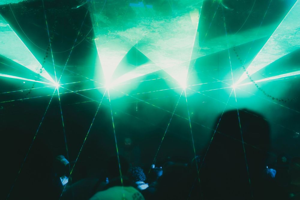 Glowing turquoise lights create a dynamic pattern against a dark background with scattered blue elements.