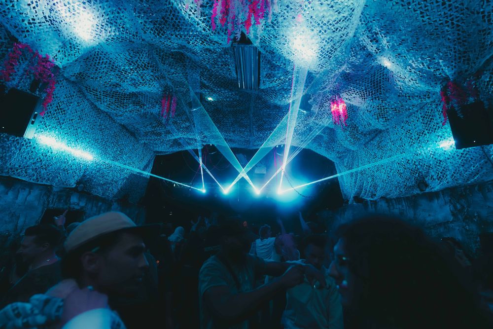 Vibrant blue lighting illuminates a dark cave-like interior space with glowing decorative elements.