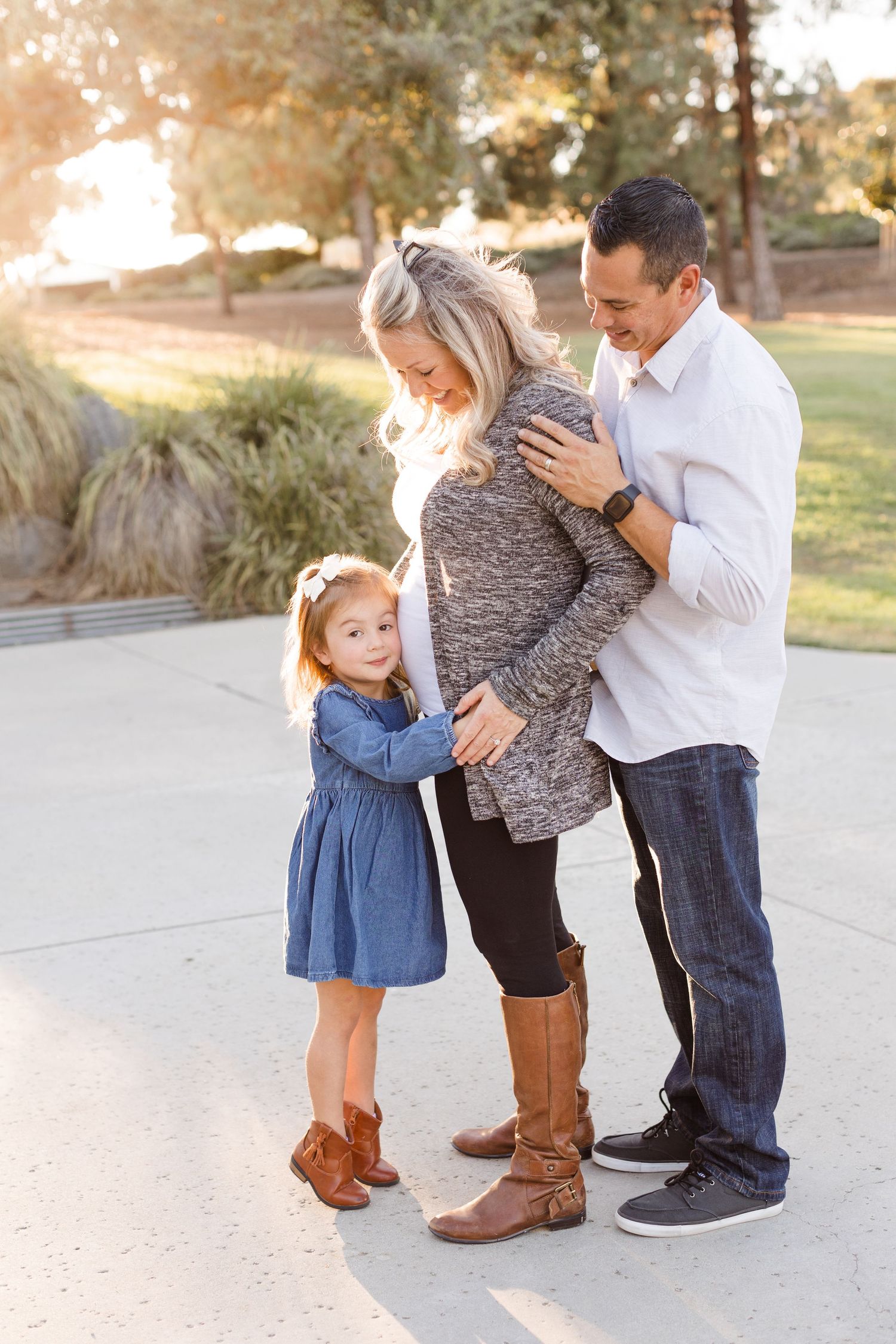 toddler girl hugging moms pregnant belly dad hugging mom