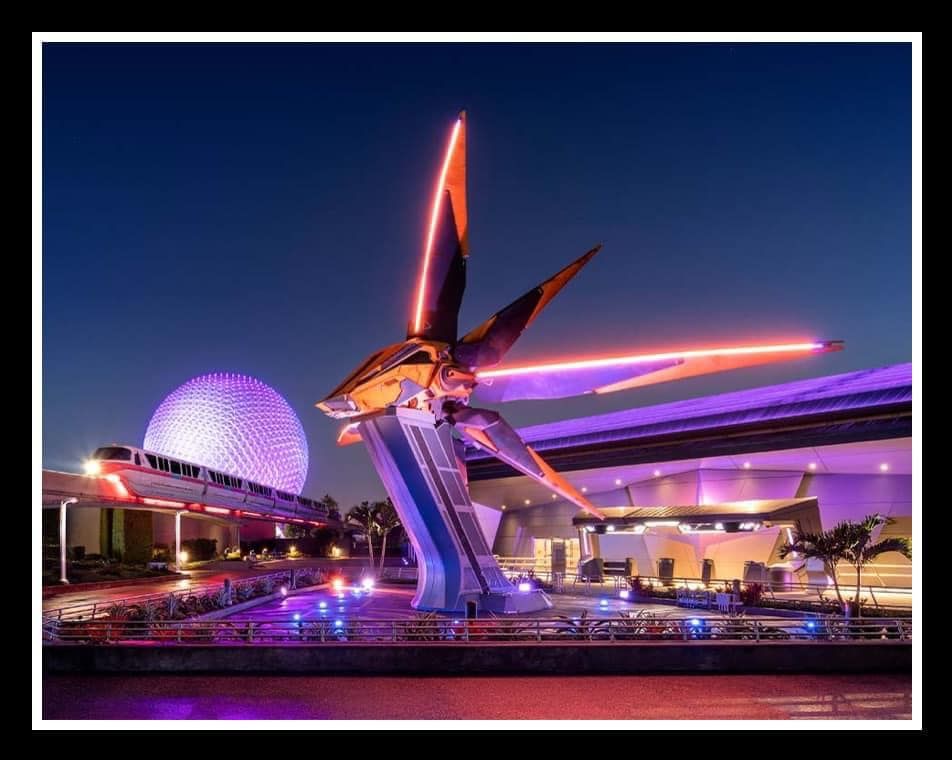 Futuristic Mission: SPACE attraction illuminated in purple and orange lights at night at EPCOT theme park.