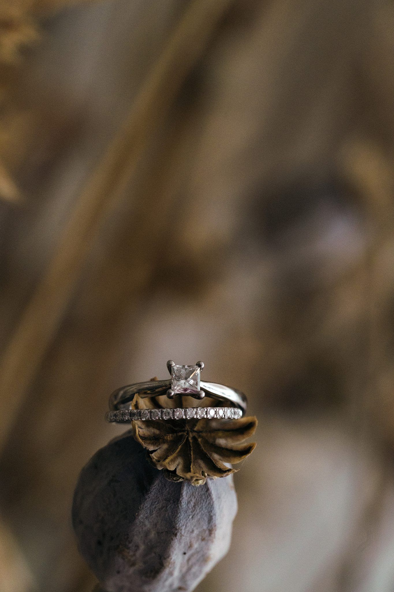 Diamond engagement ring and wedding band displayed at Healy Events, Nova Scotia on a natural textured surface in warm lighting
