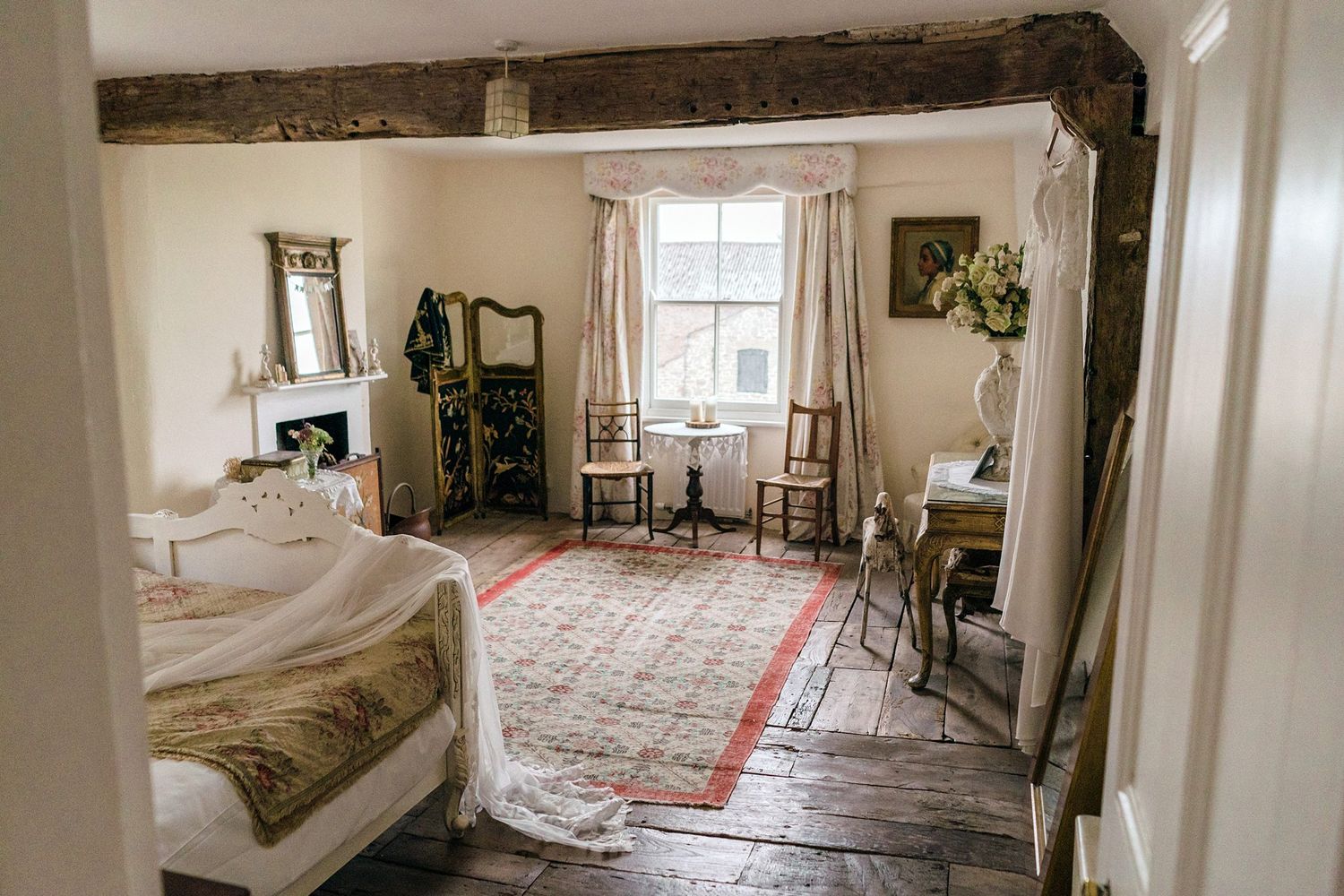 Rustic bedroom interior with exposed wooden beams and vintage furnishings with bridal wear hanging near Healy Events, NS wedding venue.