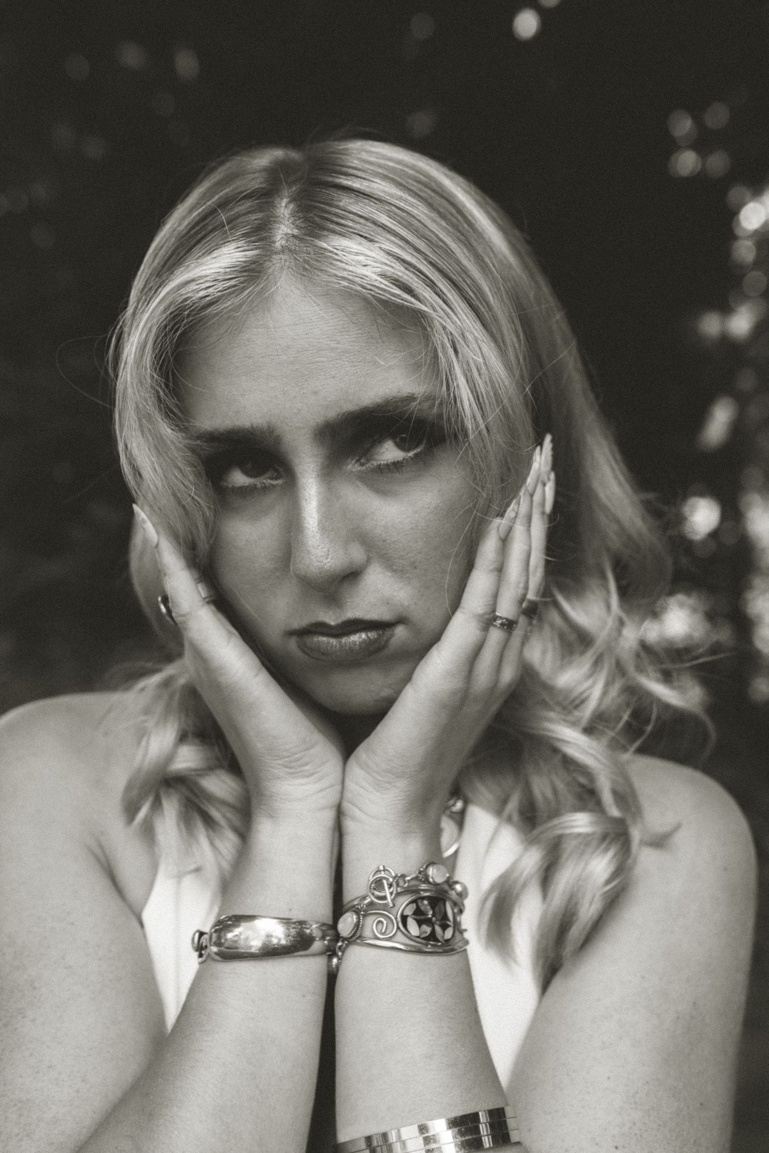 Retro-styled outdoor portrait featuring a cozy white cardigan, denim dress, cross necklace and vintage camera.