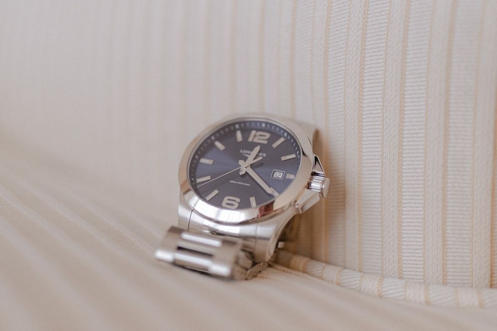 Silver wristwatch with gray dial sitting on light colored textured fabric.