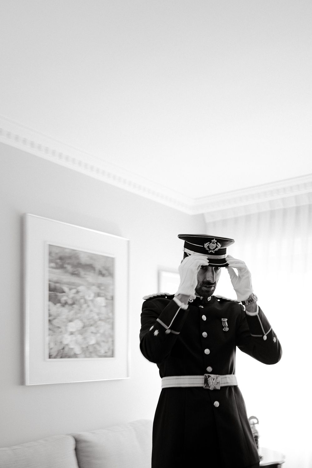 Military uniform detail in black and white against white interior wall with framed artwork.
