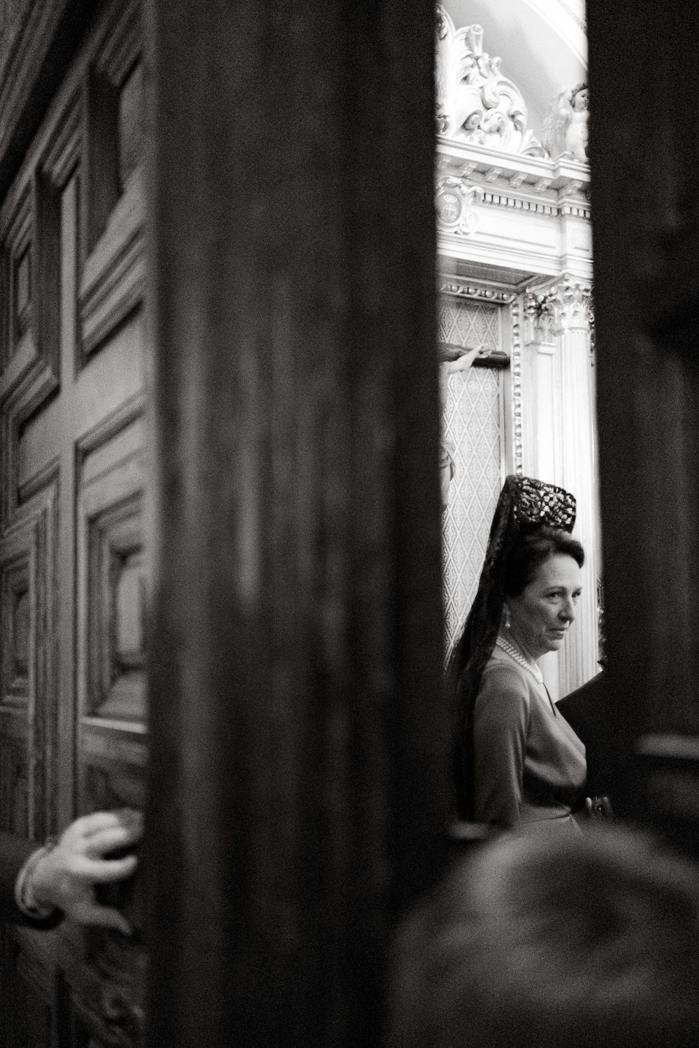 Dramatic black and white architectural photograph through doorway showing ornate classical details.
