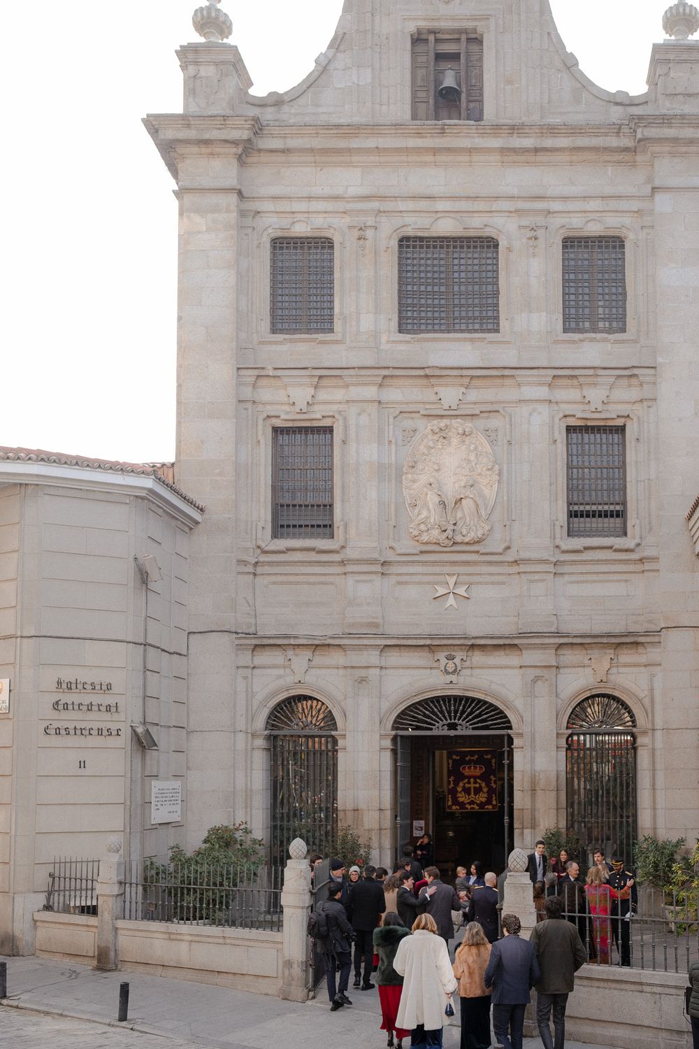 Historic stone building with classical architecture and gathered crowd at entrance.
