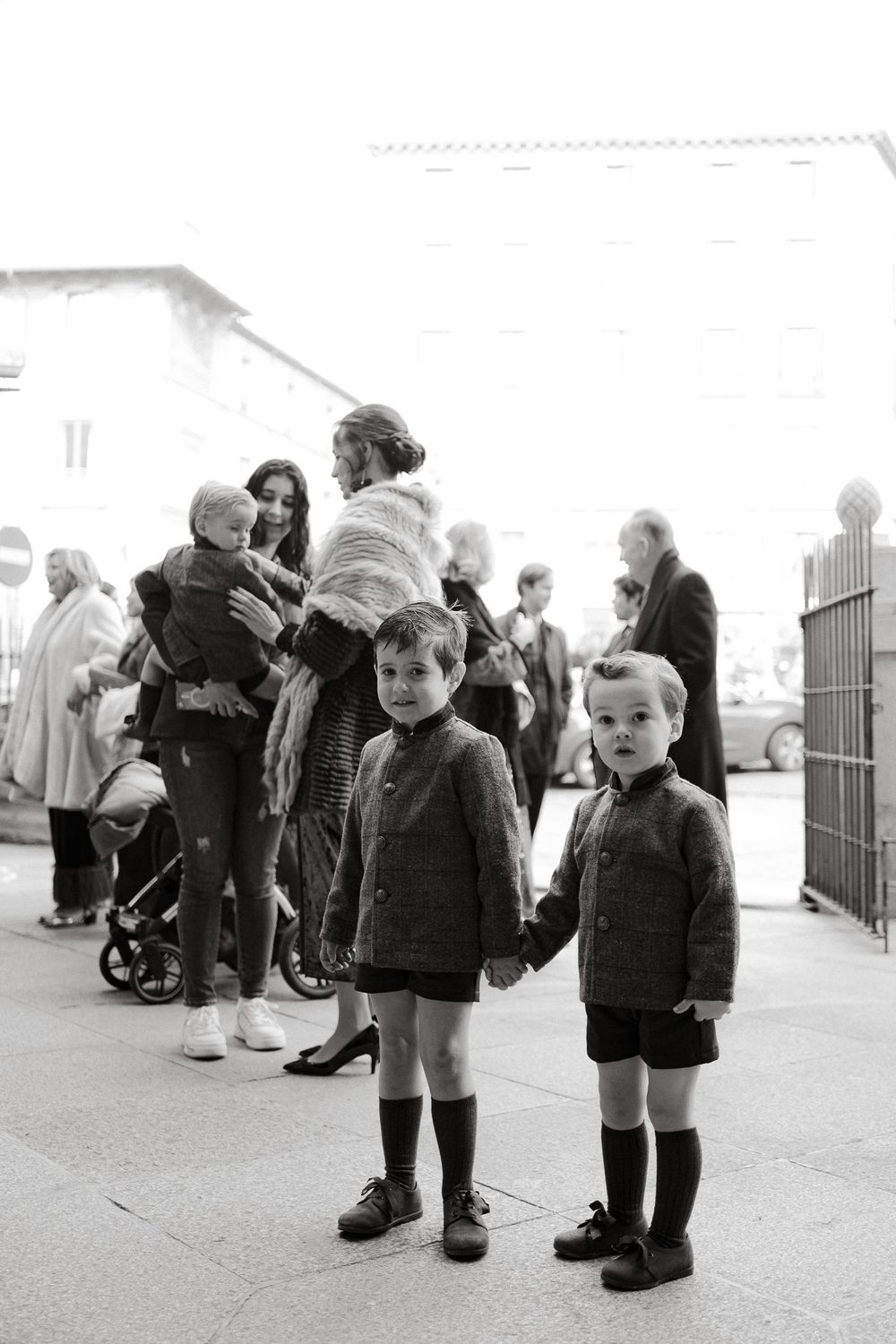 Black and white photo of children in winter coats standing among a crowd.