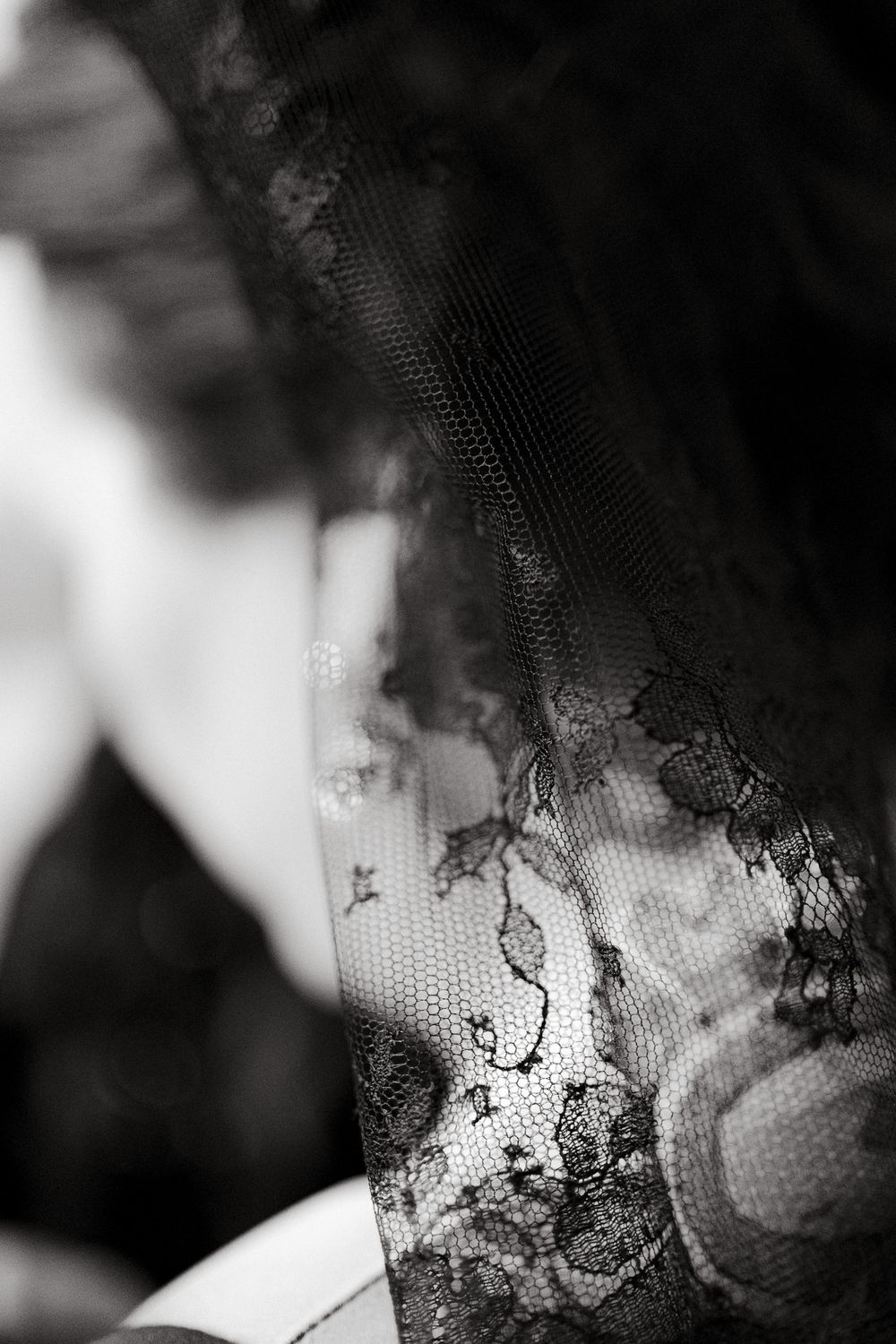 Close-up detail of black lace fabric with intricate floral pattern.