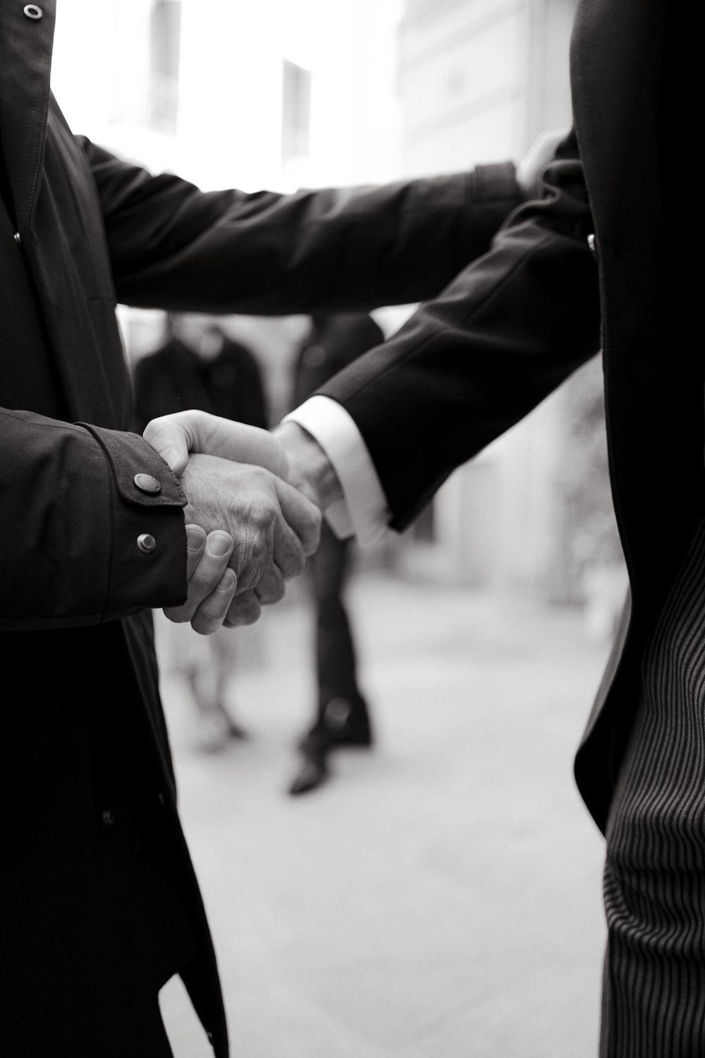 Black and white photo of formal handshake between two people in suits.