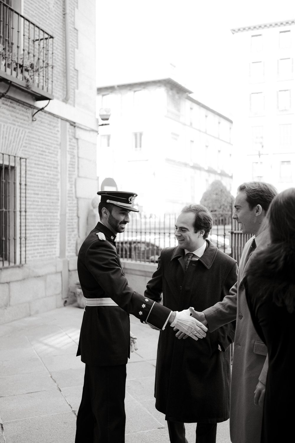 Vintage black and white photo of military greeting ceremony outside building.