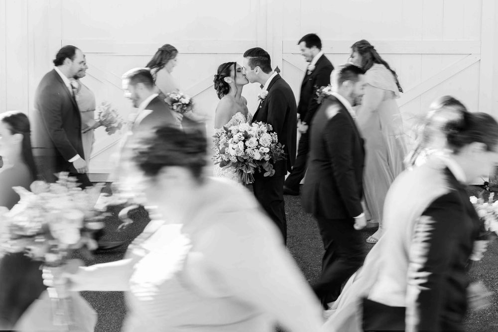 Black and white motion blur photograph of guests mingling at a wedding reception.