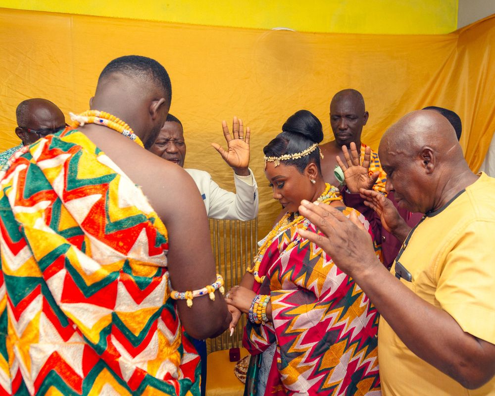 Joyful celebration with people wearing bright traditional African attire against yellow background.