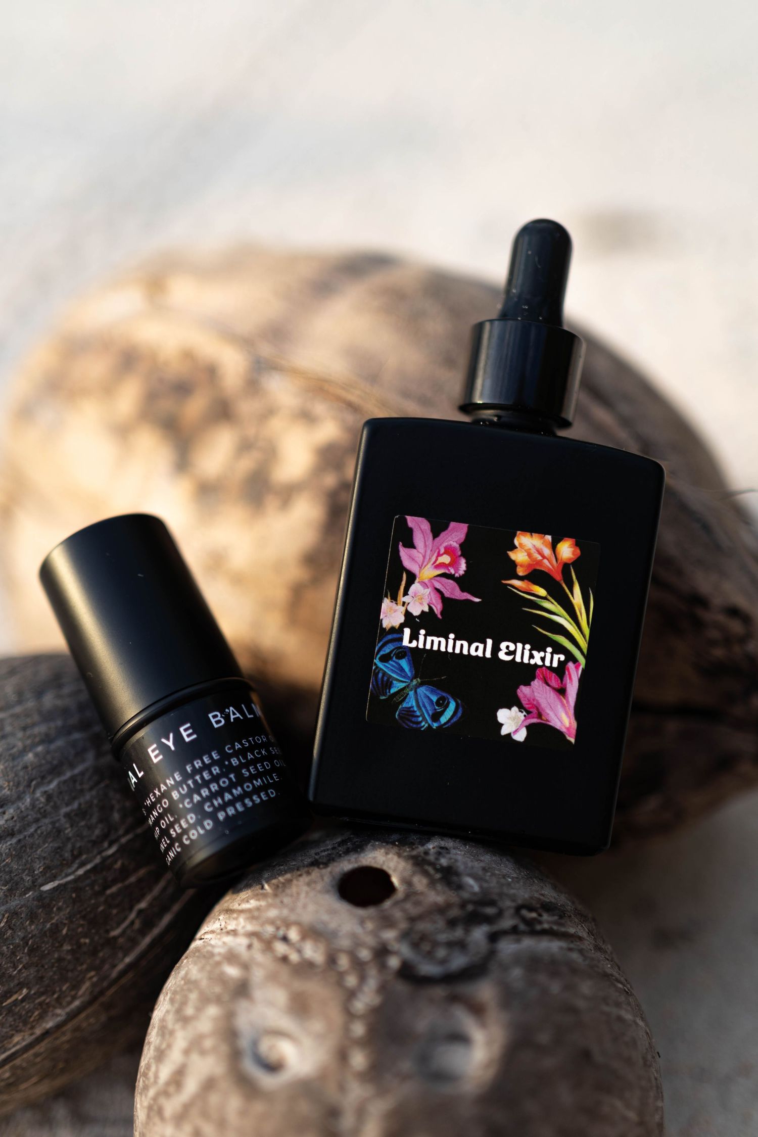Product photo of black glass bottles with floral design against natural stone background.